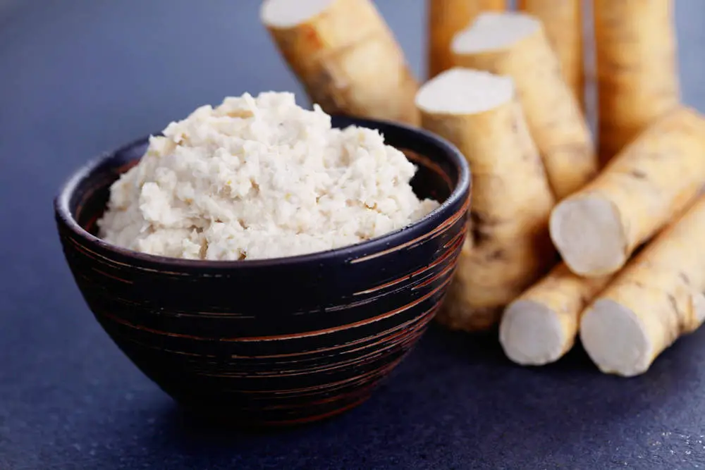 Horseradish root and grated horseradish in a bowl