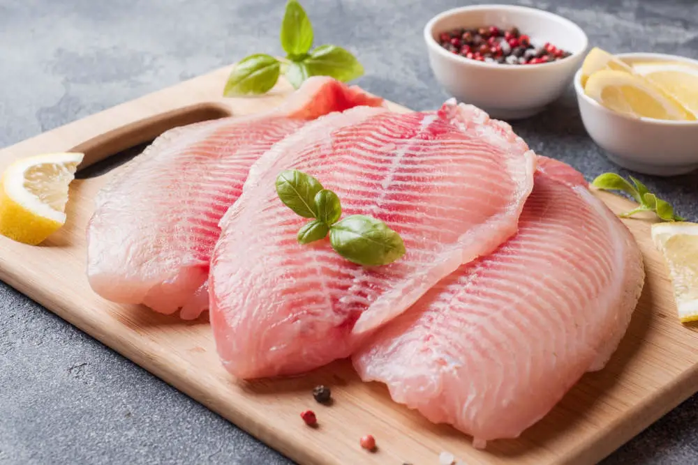 Raw tilapia fillets on cutting board